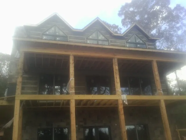 Dormers and porch framing on a large log home under construction — Roof Coating work by our crew in Leonard